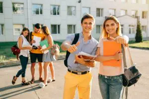 heureux-deux-jeunes-etudiants-cahiers-sacs-dos-souriant-montrant-pouce-vers-haut