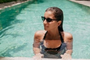 portrait-magnifique-femme-fabuleuse-portant-lunettes-soleil-elegantes-posant-dans-piscine
